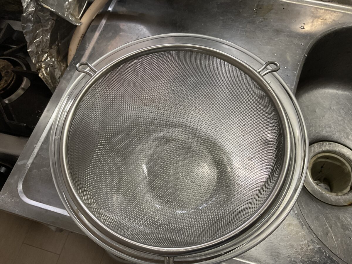パスタの湯切りに便利なステンレス製ザルの爪をボウルへ引っかけた状態