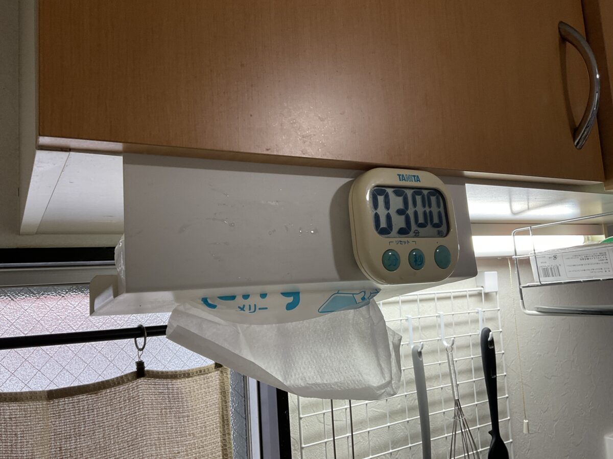 キッチンの吊戸棚下にキッチンペーパーホルダーを吊り下げて省スペース収納している様子