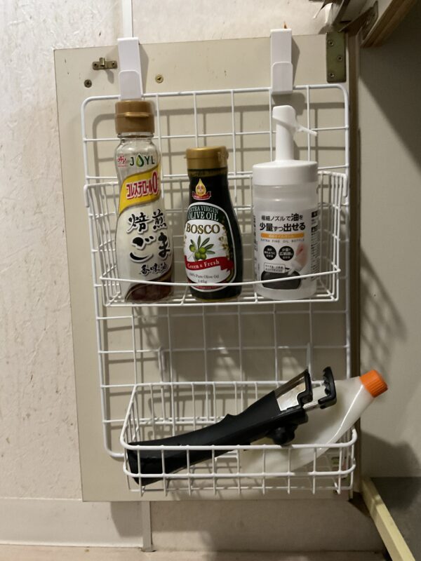 キッチン収納の扉裏にワイヤーネットとカゴを付けて調味料や小物を収納している様子