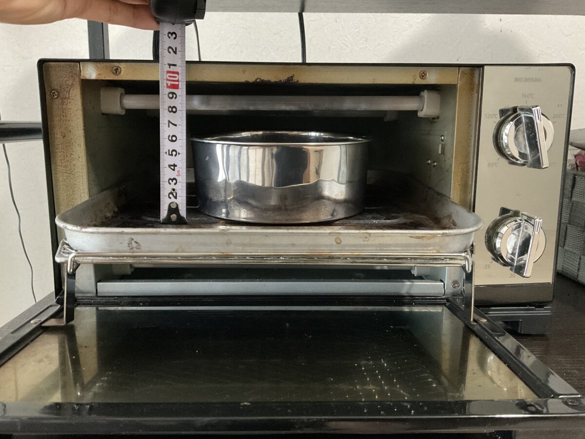 アイリスオーヤマのオーブントースターPOT-413にケーキ型を入れ、メジャーで庫内の高さを測っている様子
