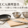 一人暮らし向けのフライパン、まな板、包丁、ボウル、ザル、計量カップなどを並べたシンプルな調理器具