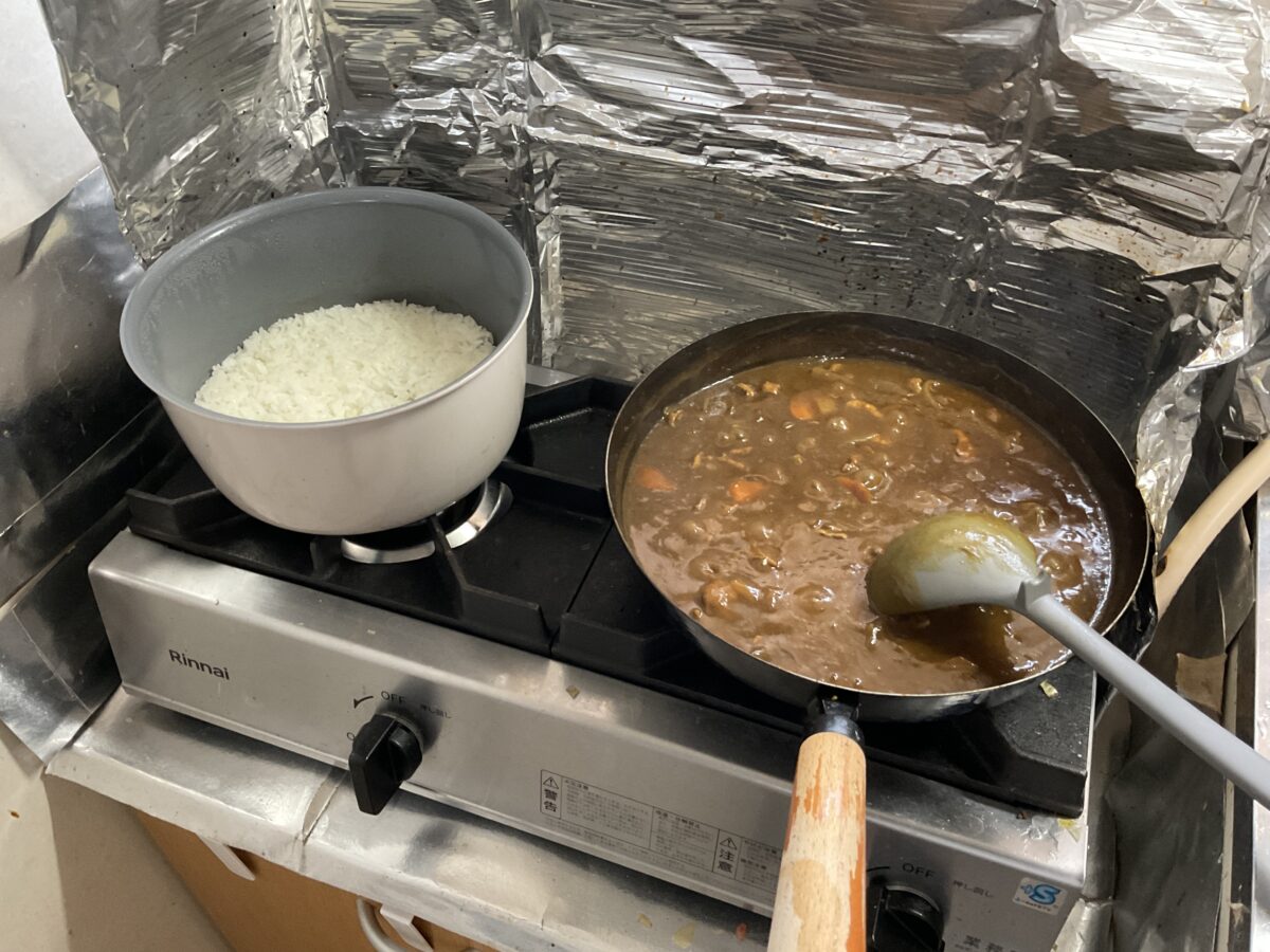 二口ガスコンロで鍋のご飯とフライパンのカレーを同時に調理している様子